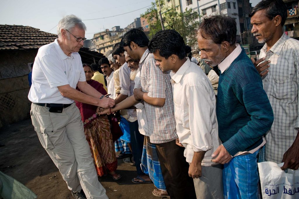 Dr. Gunter Meyer verschafft sich einen Überblick über die Patienten, die vor einer Ambulanz in Shibpur, Kolkata, auf Behandlung warten. Nur ein Stempel auf dem Handgelenk berechtigt zum Arztbesuch